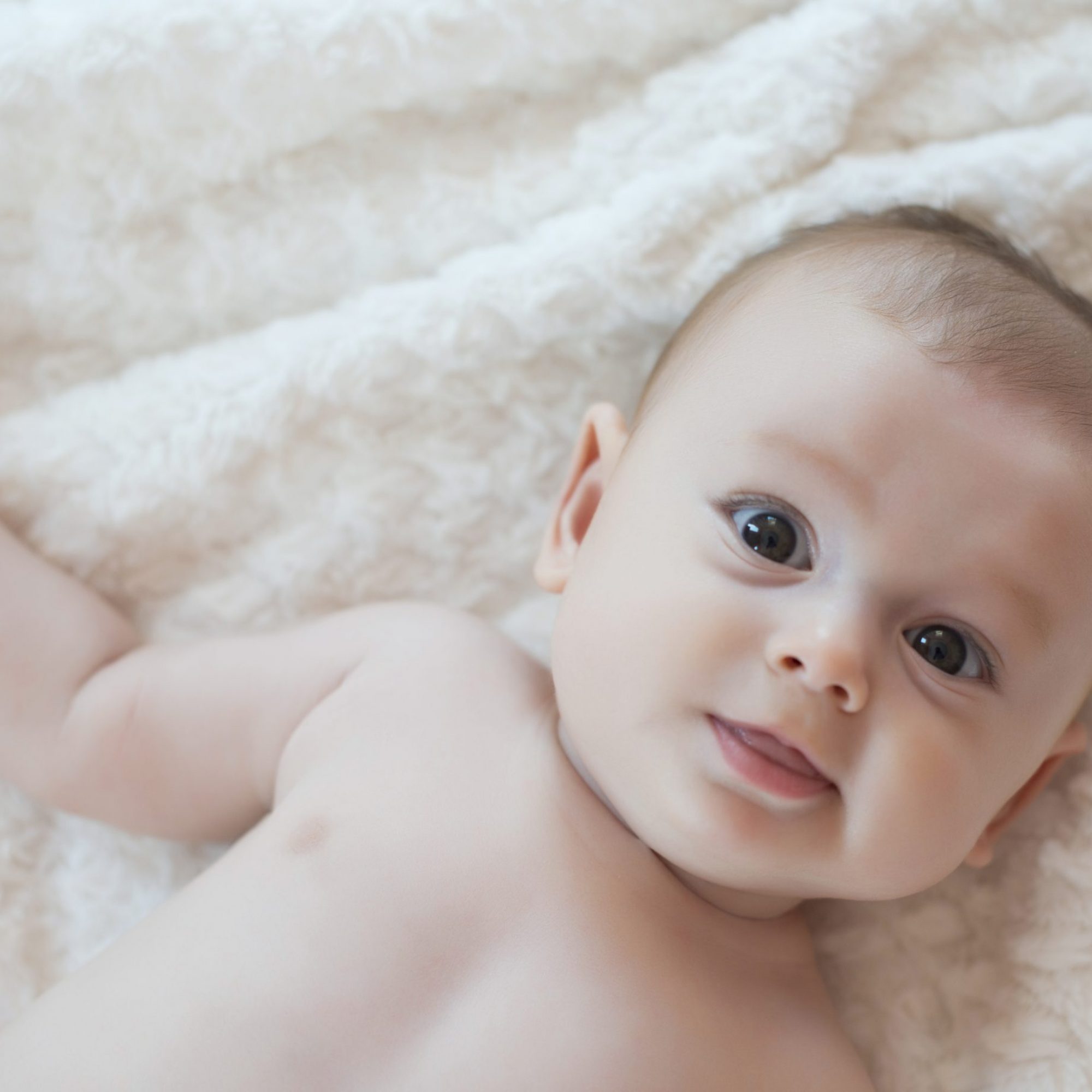 Cute baby girl lying on bed and smiling